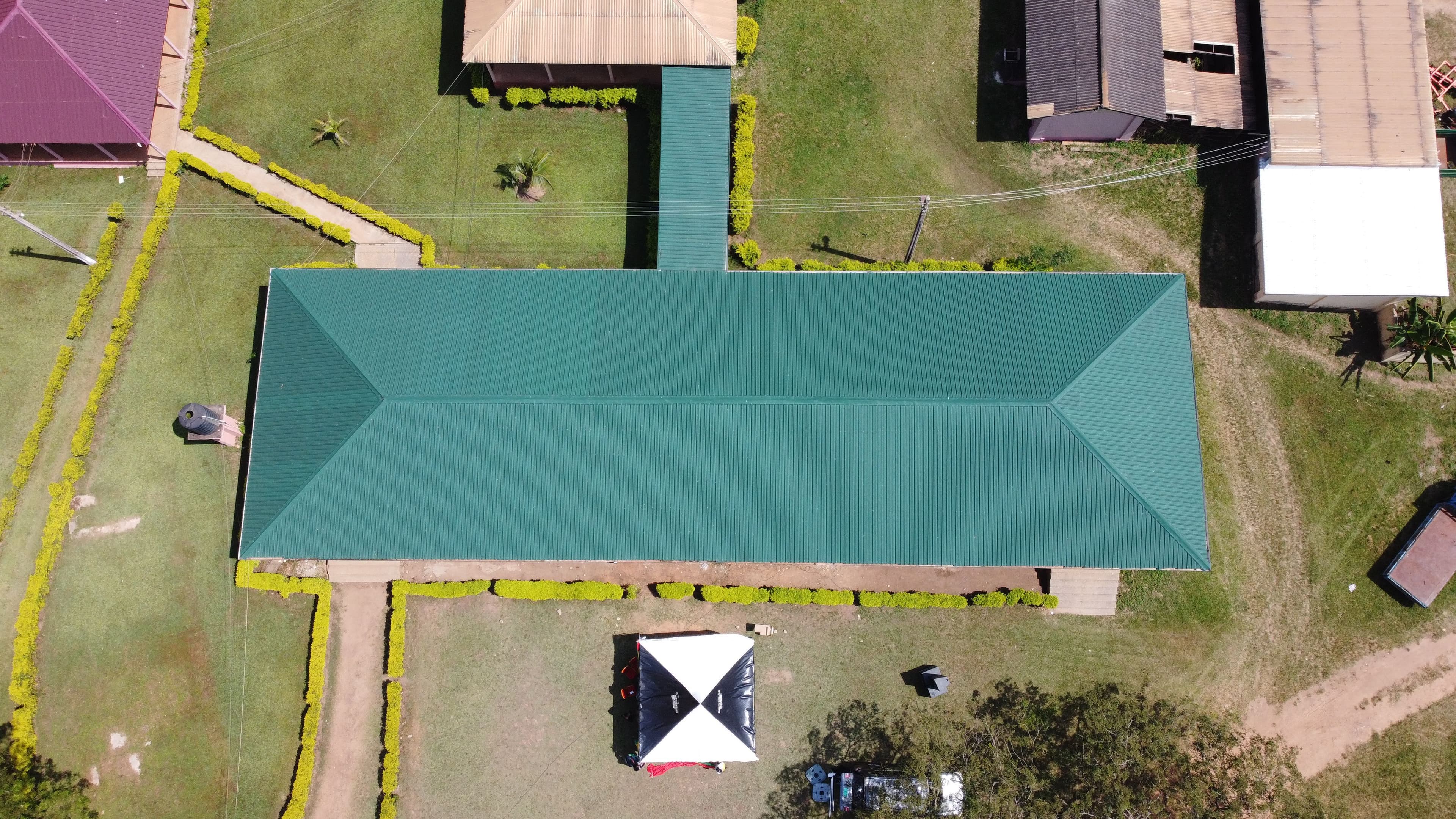 Aerial view of a rectangular building with a distinctive green roof and surrounding pathways.